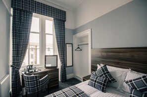 A bedroom with a bed, a desk, a chair, and a window with curtains. - Royal West End Hotel (Glasgow)