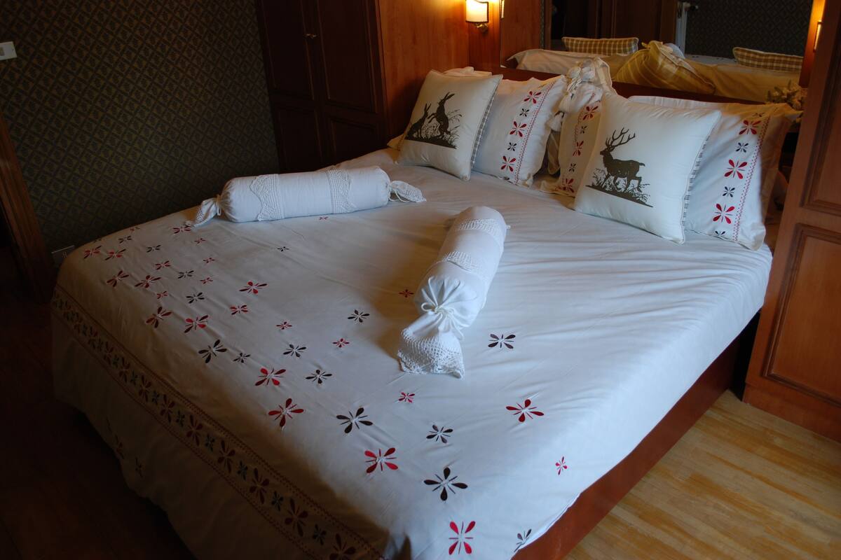 A neatly made bed with floral-patterned bedding and decorative pillows, including a deer design.