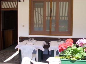A dining area with two tables set for two, each with a white tablecloth, chairs, and wine glasses. There is a window with a wooden frame and a view of the outside. - Sport Hotel Pocol (Cortina d'Ampezzo)