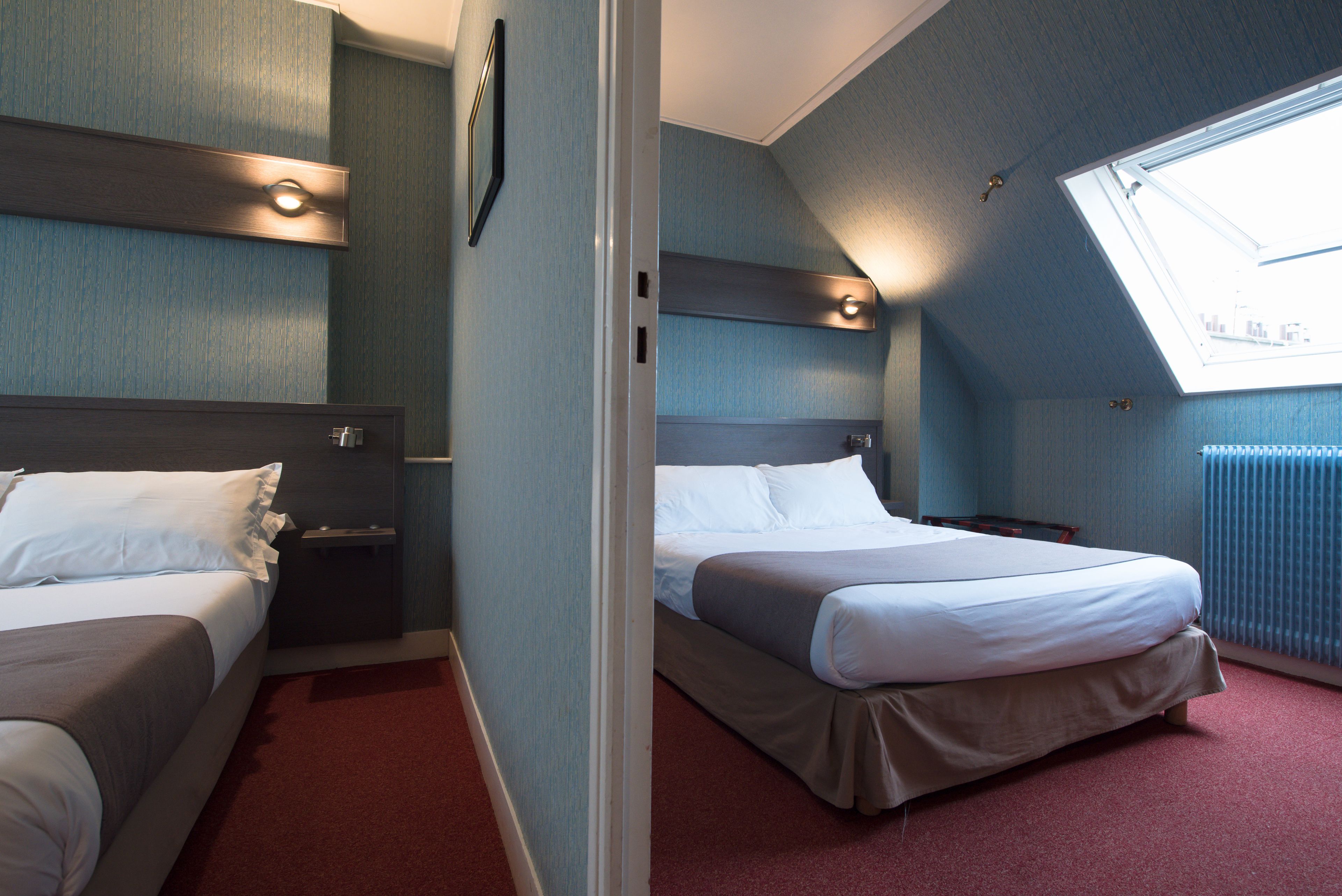 Een hotelkamer met twee bedden, een raam met uitzicht en een rood tapijt.
