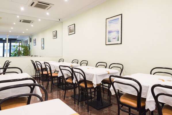 Un comedor con mesas y sillas, un espejo grande y cuadros en la pared.