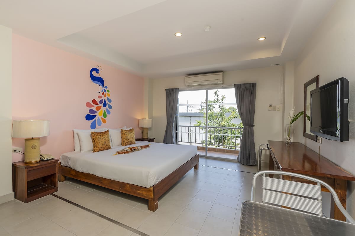 A bedroom with a bed, bedside tables, a TV, and a balcony with a view.