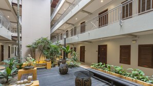 A spacious indoor courtyard with multiple levels, potted plants, and a central seating area.