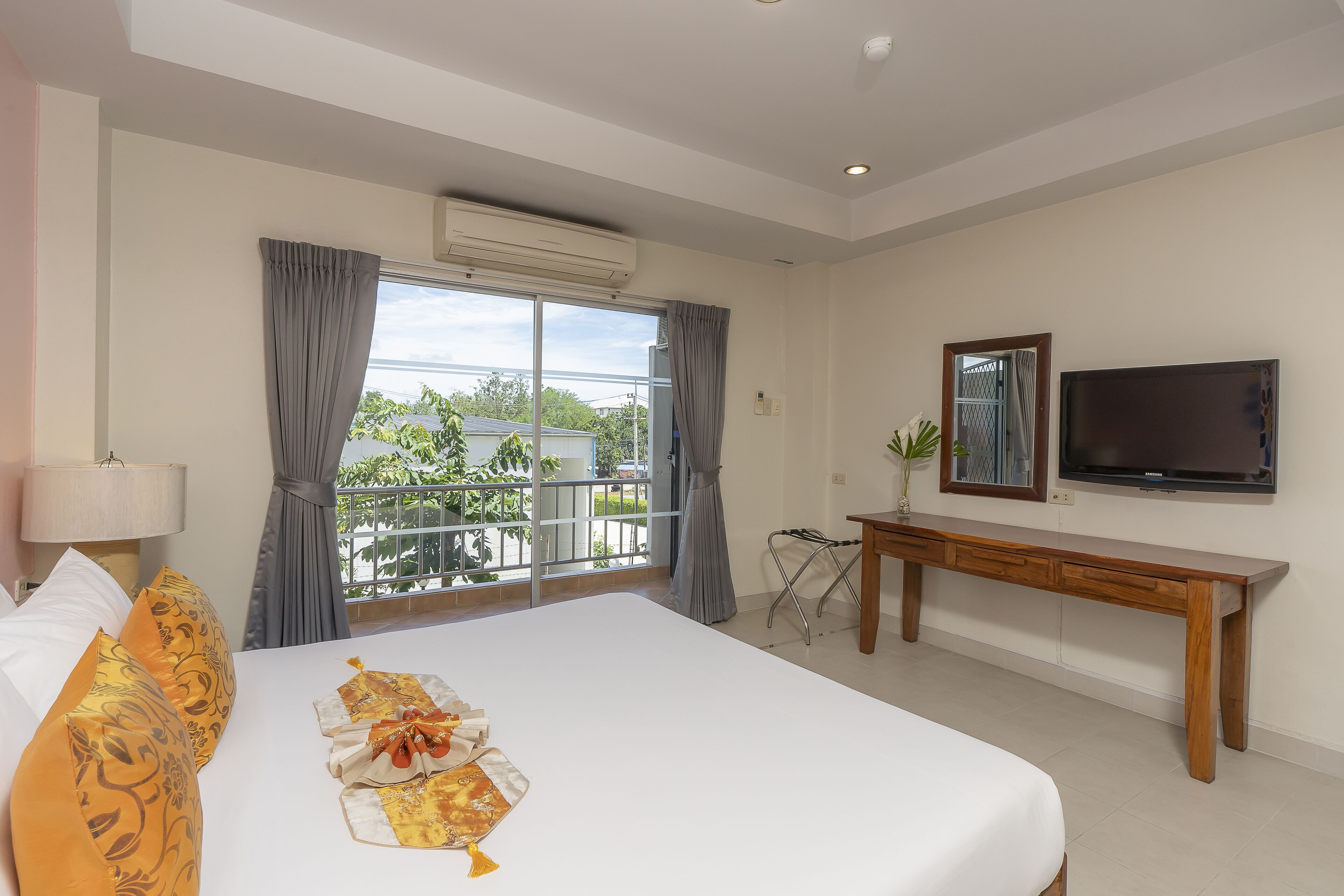 A hotel room with a large bed, a TV, a desk, and a window with curtains.