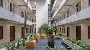 A multi-level atrium with a central open space surrounded by potted plants and seating areas.
