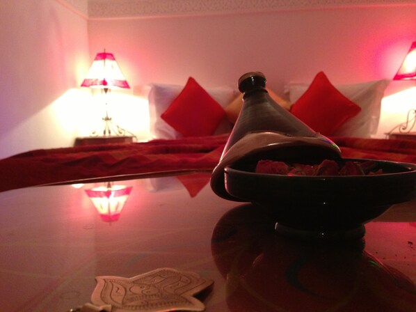 A room with a bed, red pillows, a lamp, and a decorative object on a table.
