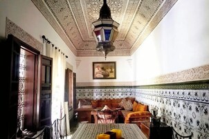 Una habitación con techo estampado, un sofá, una mesa con fruta y una lámpara colgante.