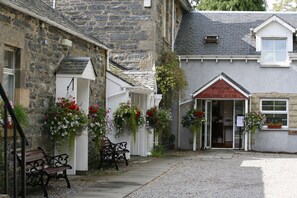 Un bâtiment en pierre sur lequel on peut lire l’inscription : « Bienvenue à Columba House ». On y trouve des bancs et des jardinières à l’extérieur.