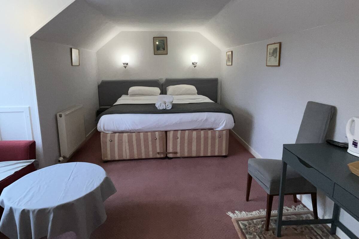 Une chambre à coucher avec un lit, un bureau, une chaise et une petite table.