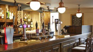 A bar area with multiple taps, a counter, and wooden cabinets. - Woolpack Inn Beckington by Greene King Inns (Frome)