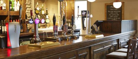 A bar area with multiple taps, a counter, and wooden cabinets.