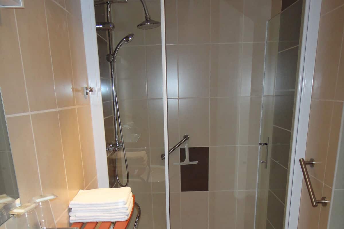 A modern bathroom with a glass-enclosed shower, a sink with a mirror, and a towel rack.
