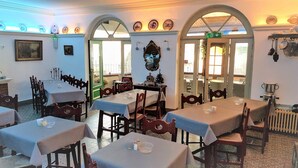 A dining area with tables set for two, wooden chairs, and a decorative mirror on the wall. - Hotel Cobut (Onhaye)