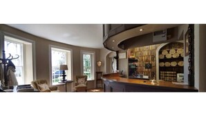 Un salón amplio con un gran ventanal, chimenea, estantería y zona de comedor.