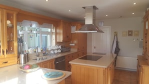 Una cocina con armarios de madera, una campana extractora de acero inoxidable, una isla grande con fregadero y un refrigerador.