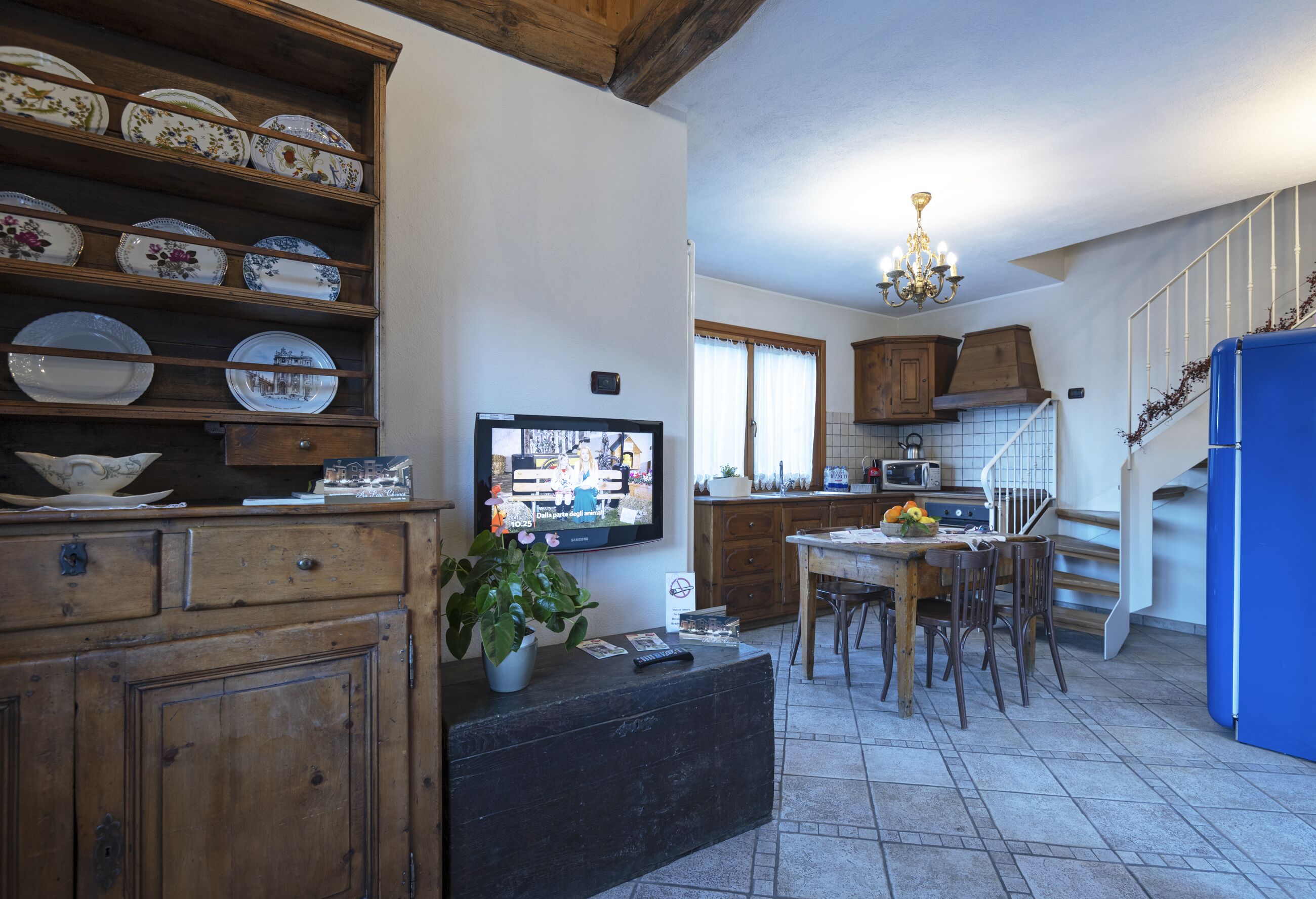 Una cocina con armarios de madera, una mesa de comedor y un televisor.