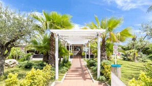 A covered walkway leading to a building with a sign indicating no parking. - Hotel Maja (Pescara)