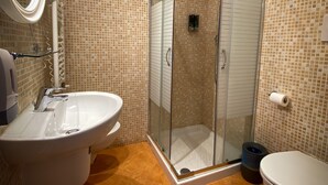 A bathroom with a glass-enclosed shower, a sink, and a toilet. - Hotel Arena (Verona)