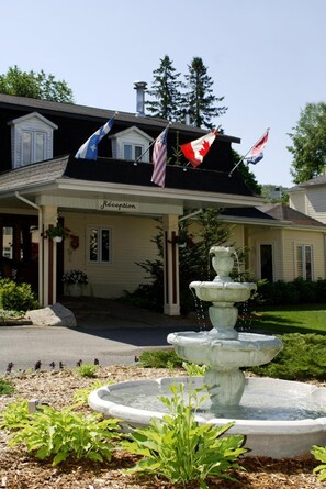 A building with a reception area, a stone fountain, and multiple flags. - Relais St-Denis (Saint-Sauveur)