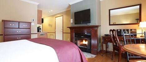 Une chambre d’hôtel équipée d’un lit, d’une cheminée, d’une télévision, d’un bureau et d’une chaise.
