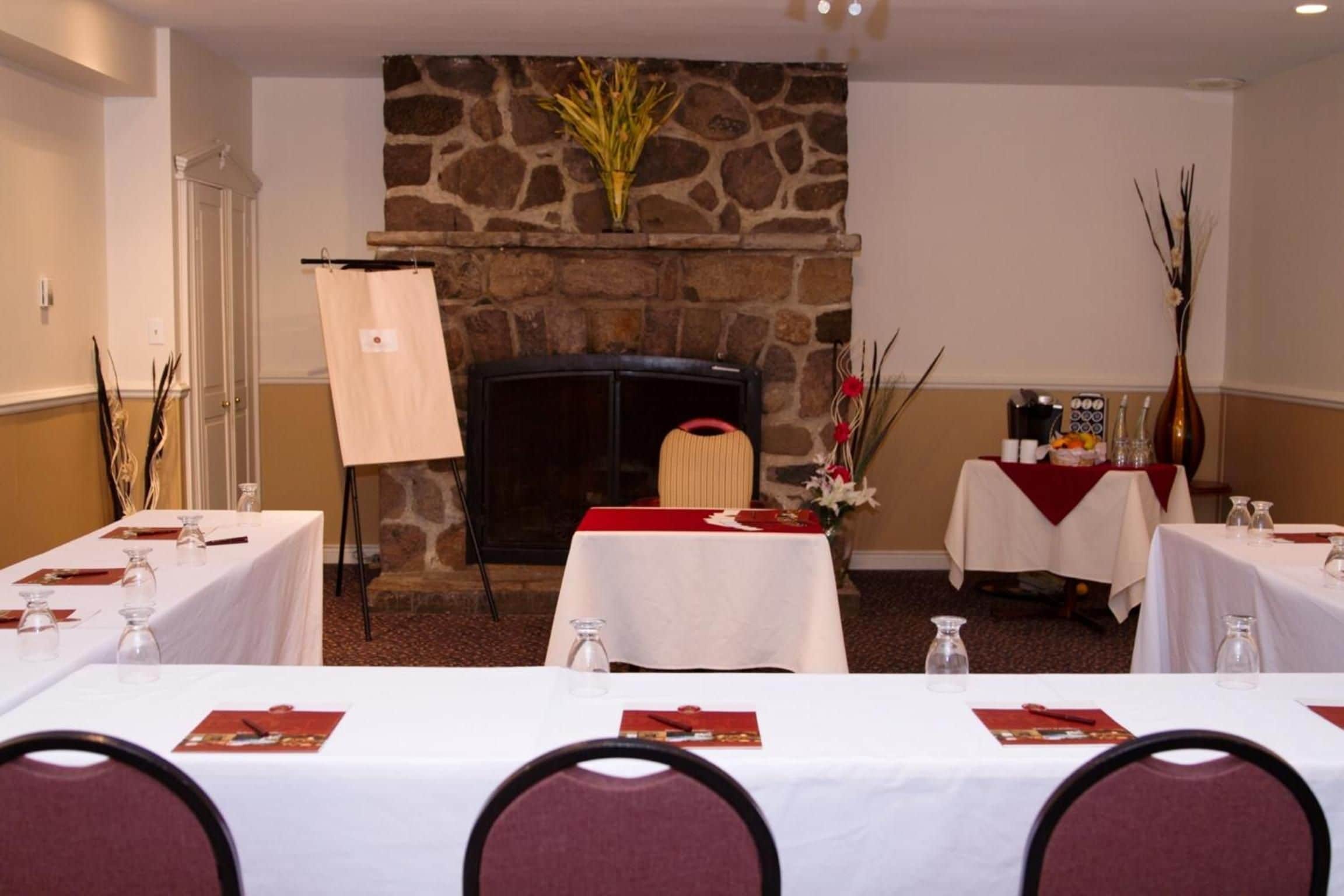 A conference room with a stone fireplace, white tables, and chairs.