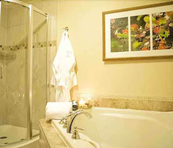 A bathroom with a glass-enclosed shower, a bathtub, and a framed painting on the wall. - Relais St-Denis (Saint-Sauveur)