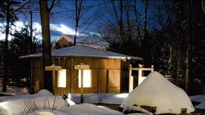 Una cabaña de madera rodeada de nieve y árboles.