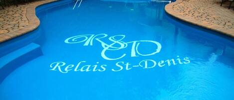 Una piscina con un logotipo que dice "R&D Relais St-Denis" reflejado en la superficie del agua.