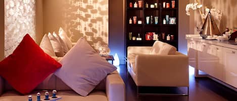 A modern living room with a sofa, ottoman, and a bookshelf.