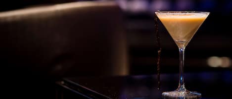 A martini glass with a frothy drink on a bar.