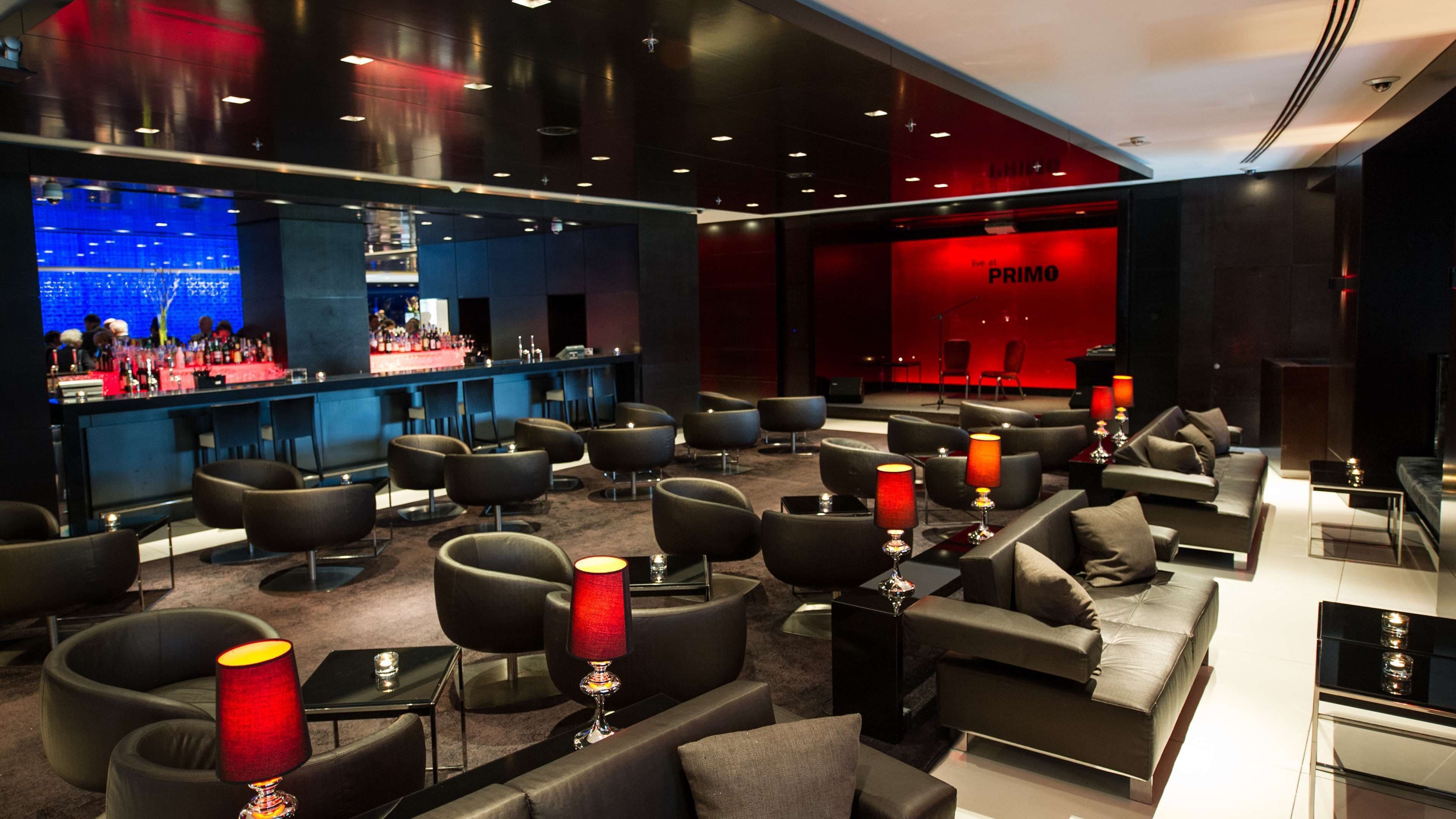 A modern lounge area with sofas, tables, and a bar.