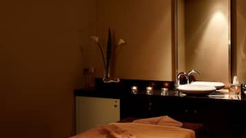 Relax in a serene spa room with a massage table, sink, and soothing light fixture.