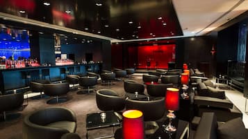 A modern lounge area with sofas, tables, and a bar.