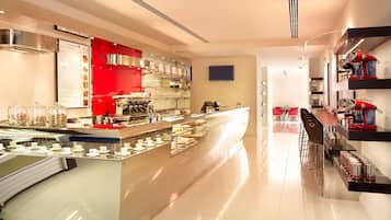 A modern café with a central counter, glass display cases, and shelves with various items.
