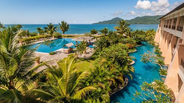 A resort with a large pool surrounded by palm trees and a view of the ocean. - The Natsepa Resort & Conference Center (Salahutu)