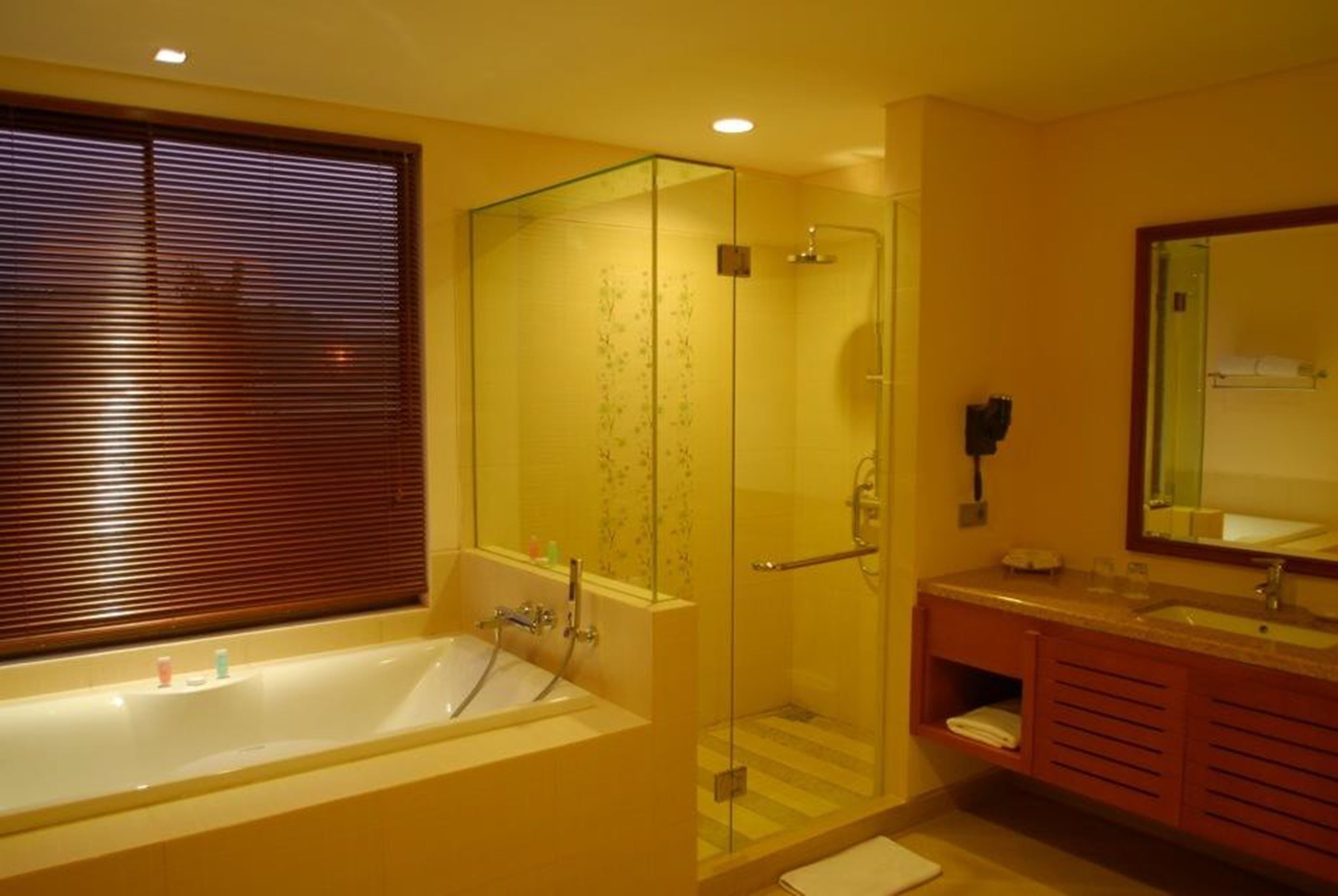 Un baño moderno con ducha de vidrio, bañera y tocador con espejo.