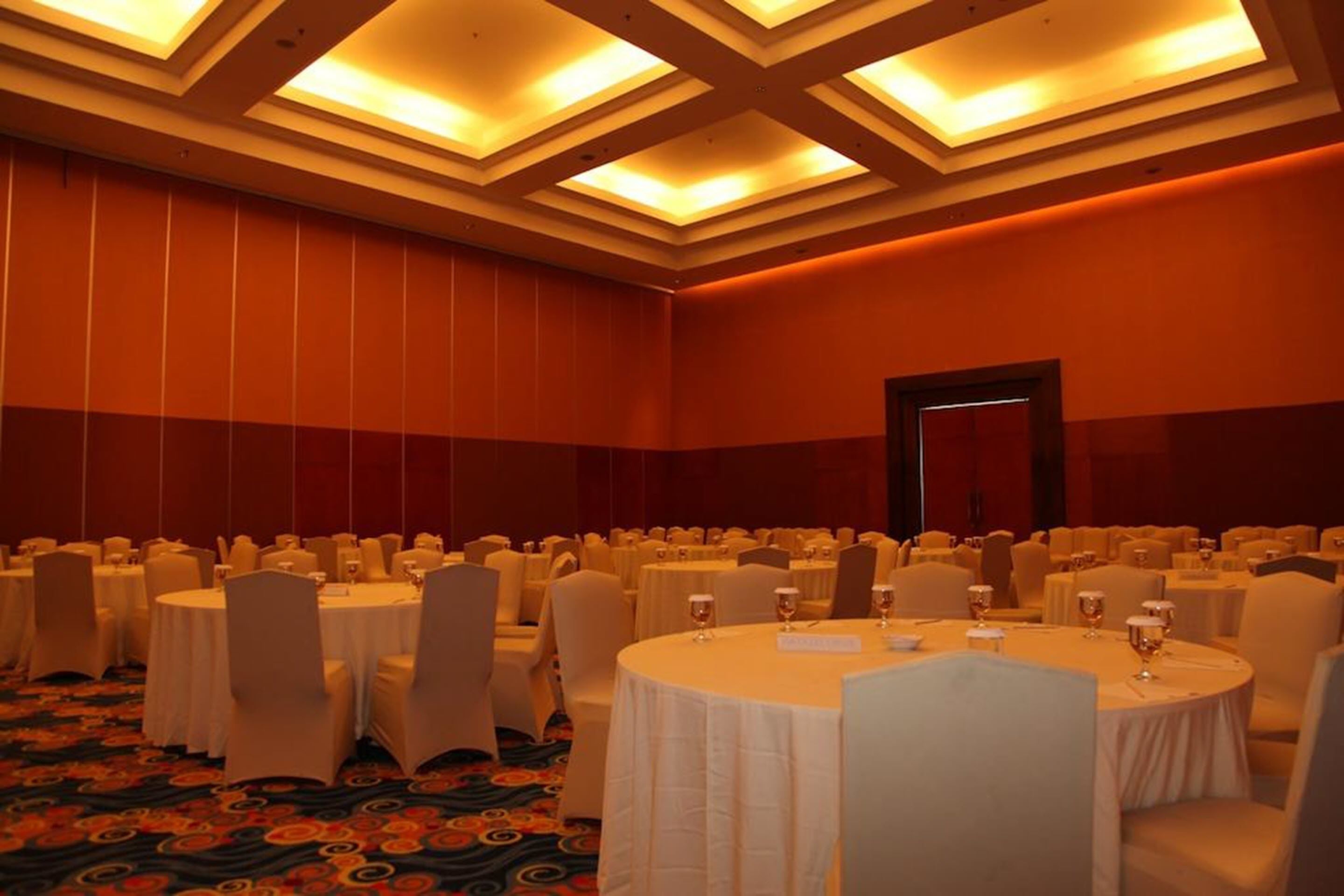 Un salón de banquetes con mesas redondas, manteles blancos y sillas.
