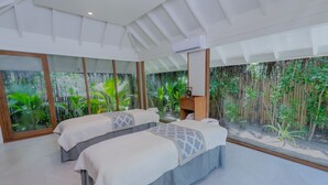 A room with two beds, large windows, and a view of greenery. - Anantara Kihavah Maldives Villas (Kihavah)
