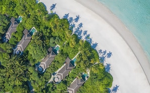 An aerial view of a resort with multiple bungalow-style accommodations, a sandy beach, and lush greenery. - Anantara Kihavah Maldives Villas (Kihavah)