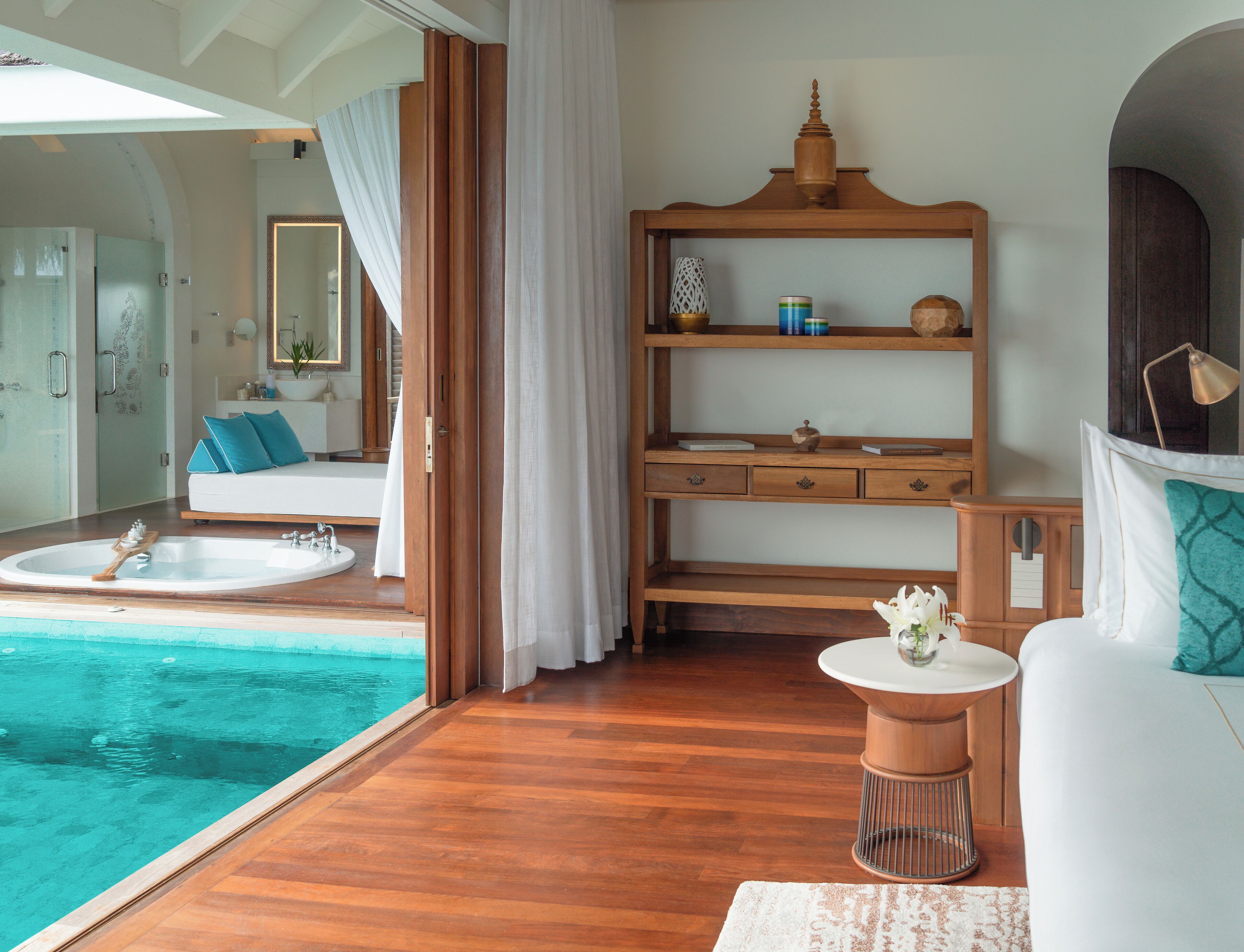 A modern bathroom with a large bathtub, a wooden vanity, and a small table with a vase.