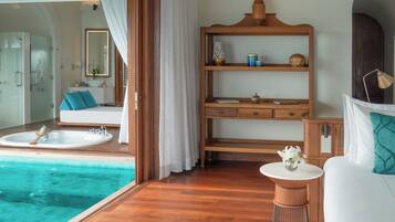 A modern bathroom with a large bathtub, a wooden vanity, and a small table with a vase.