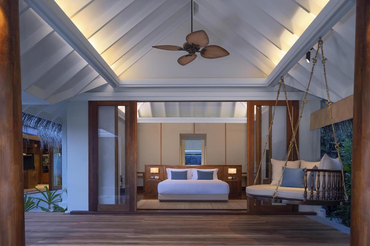 A spacious bedroom with a large bed, a hanging swing, and a ceiling fan.