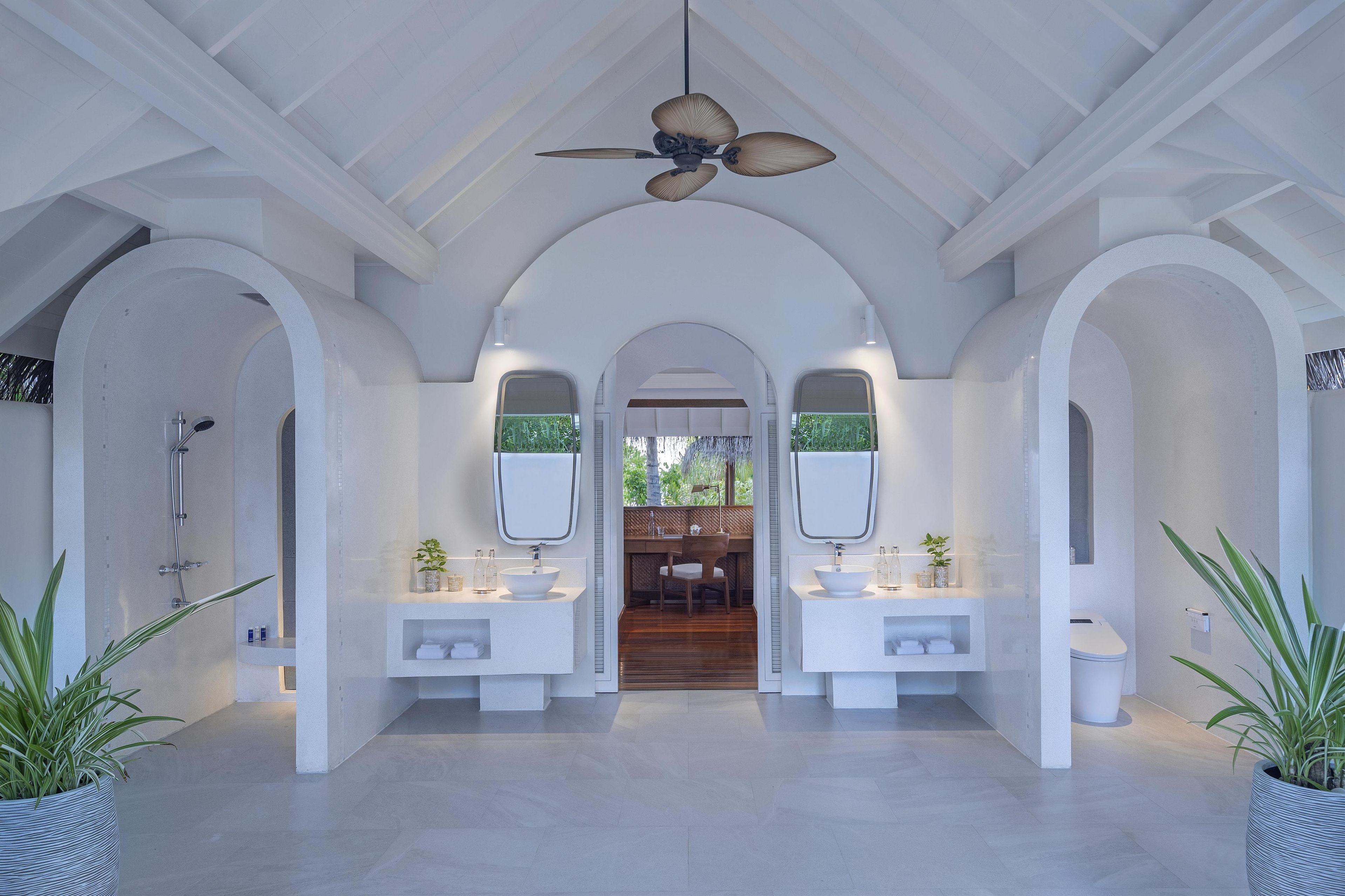 Un bagno moderno con due lavabi, una doccia e una ventola a soffitto.