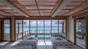 Una habitación con dos camas, un ventanal y vista al océano.