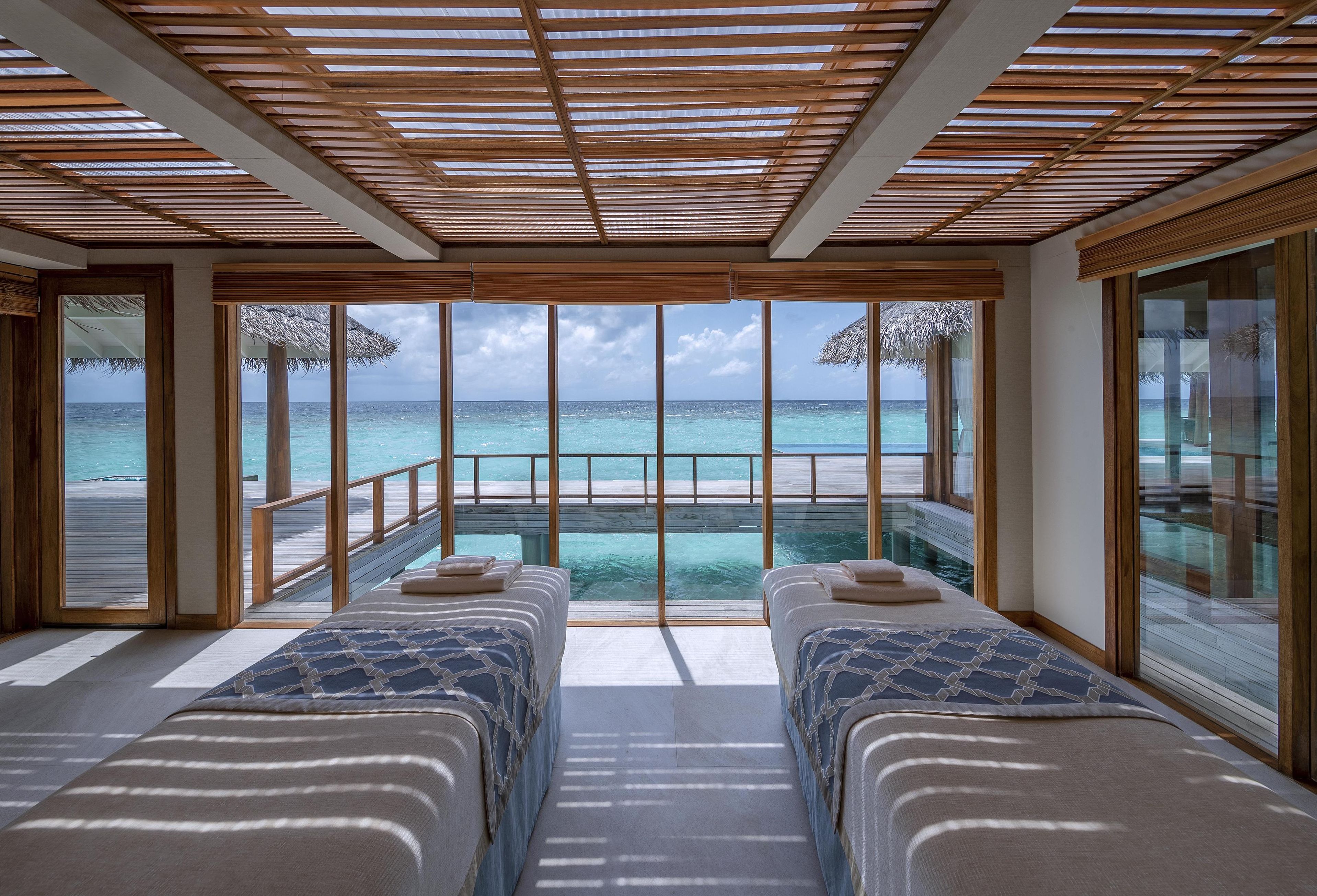 Una habitación con dos camas, un ventanal y vista al océano.