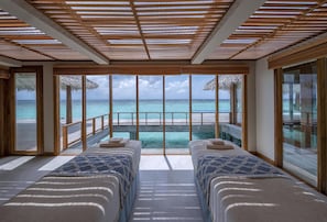 Une chambre avec deux lits, une grande fenêtre et une vue sur l’océan.