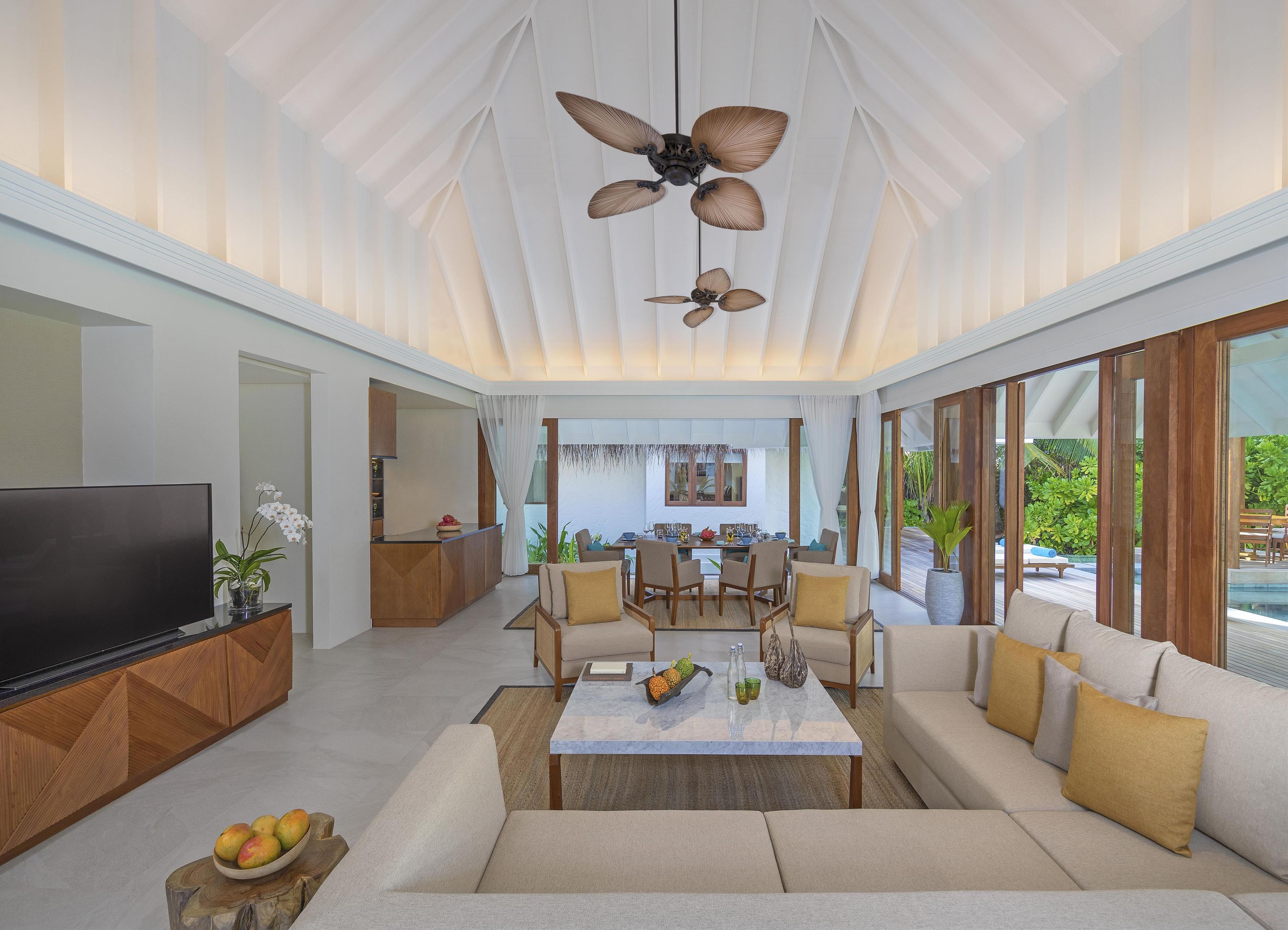 A spacious living area with a large TV, comfortable seating, a dining area, and a ceiling fan.