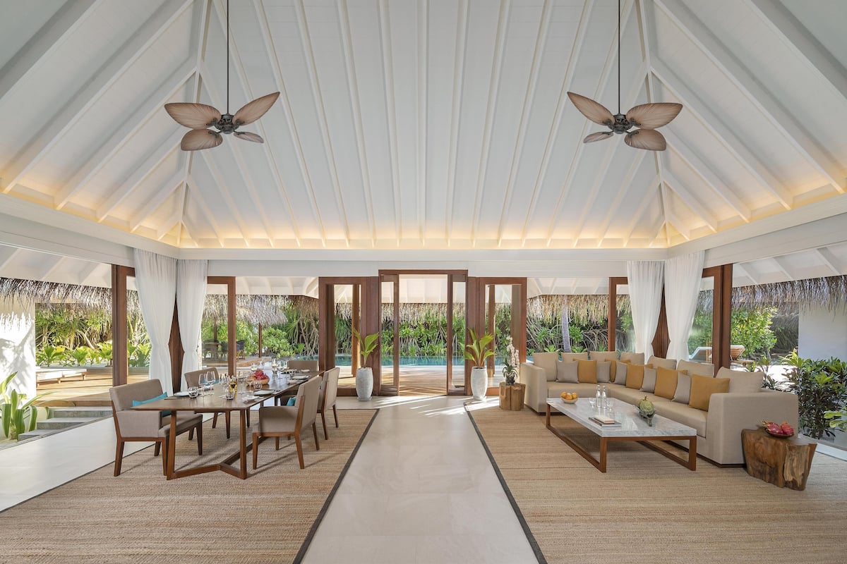 A spacious living area with a high ceiling, large windows, and a view of the outdoors.