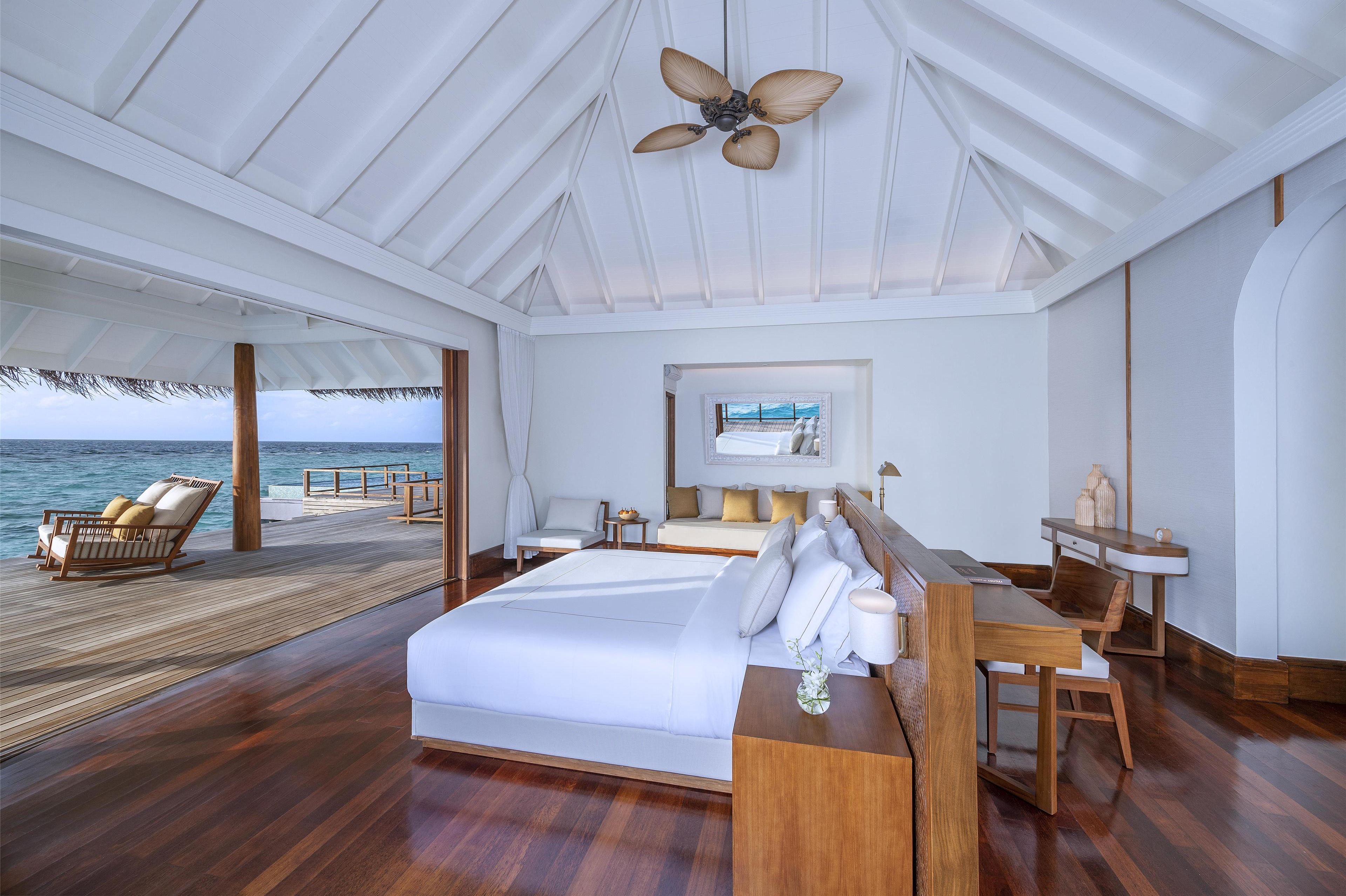 A spacious bedroom with a large bed, a desk, and a view of the ocean.