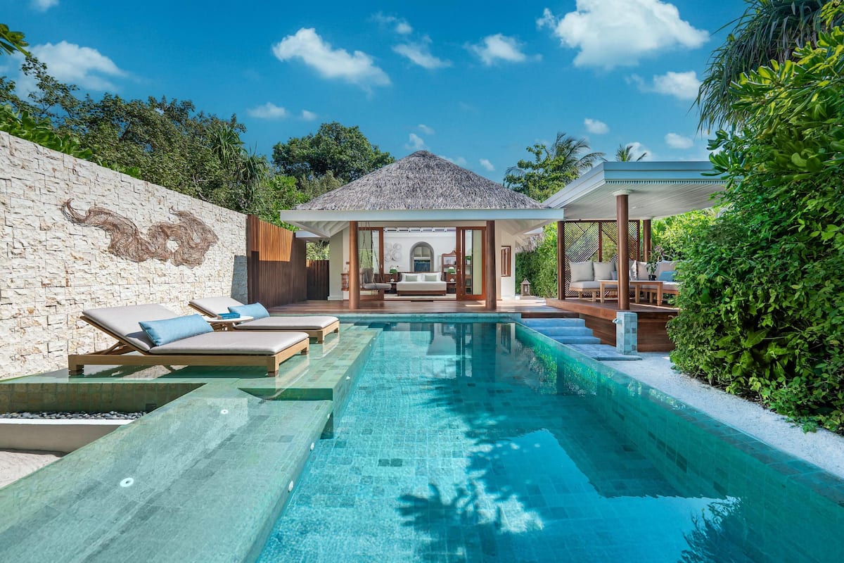 A pool area with lounge chairs and a covered seating area.